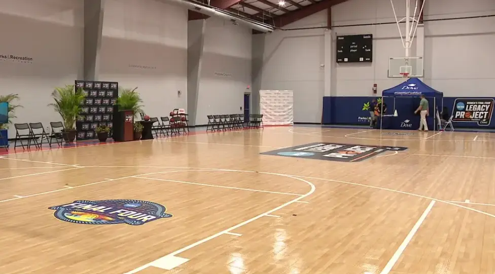 An empty basketball court after the Women's Final Four Championship, with scattered confetti and streamers. The stadium is quiet, reflecting the aftermath of the celebration.