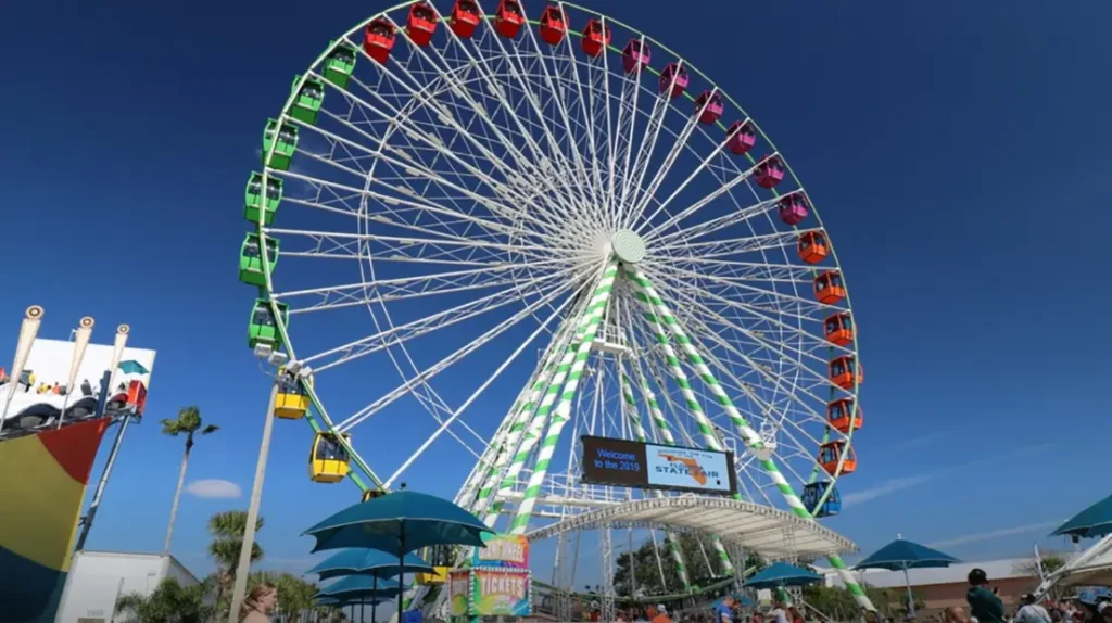 A vibrant sunset scene showing the Ferris wheel and rides lighting up the Florida Strawberry Festival in Plant City.